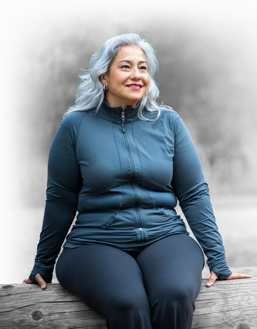 Female model in blue tracksuit sitting on log