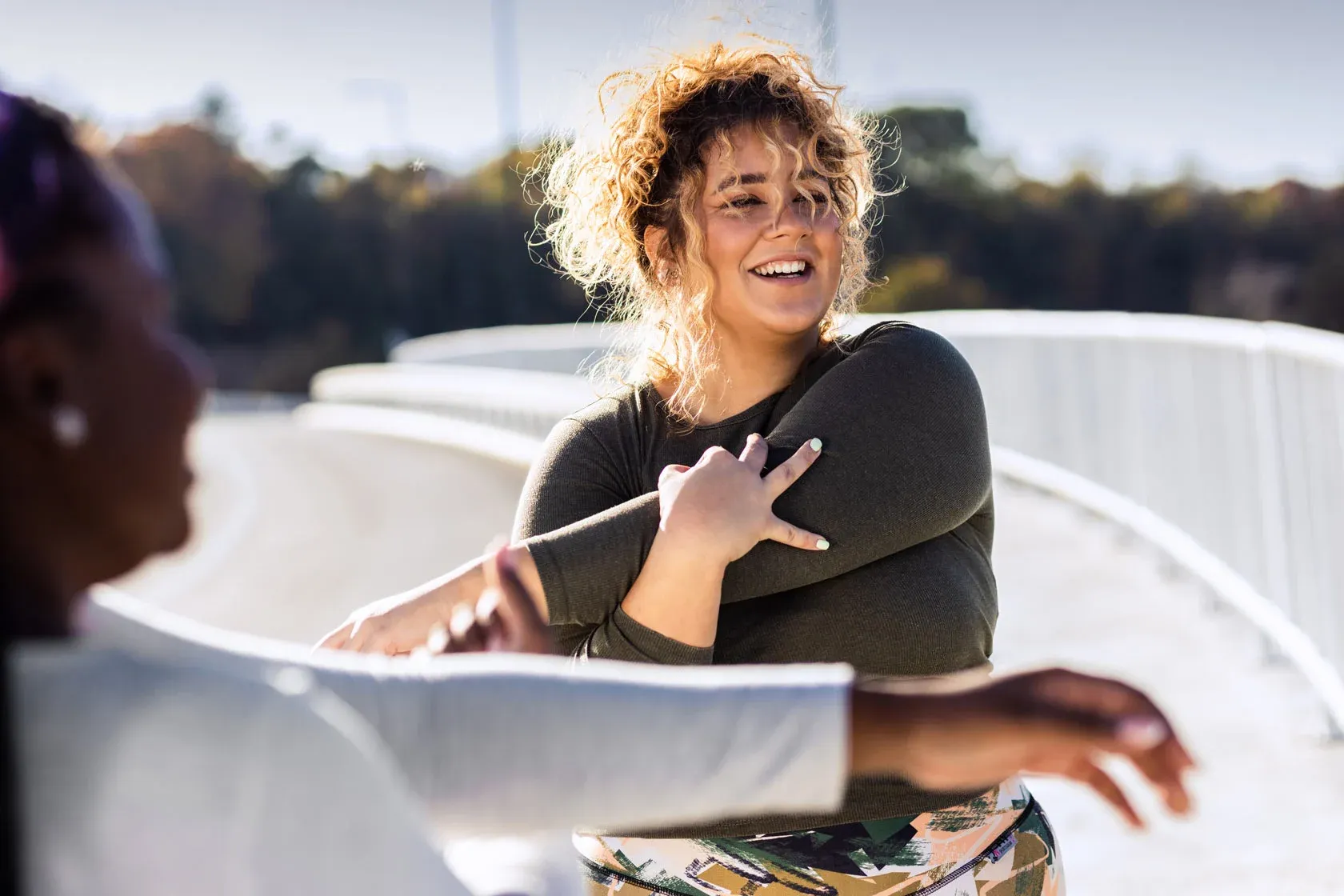 Two women stretching outside on a sunny day.