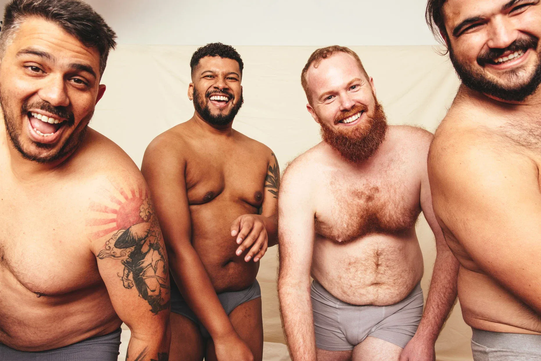Four men smiling in underwear.