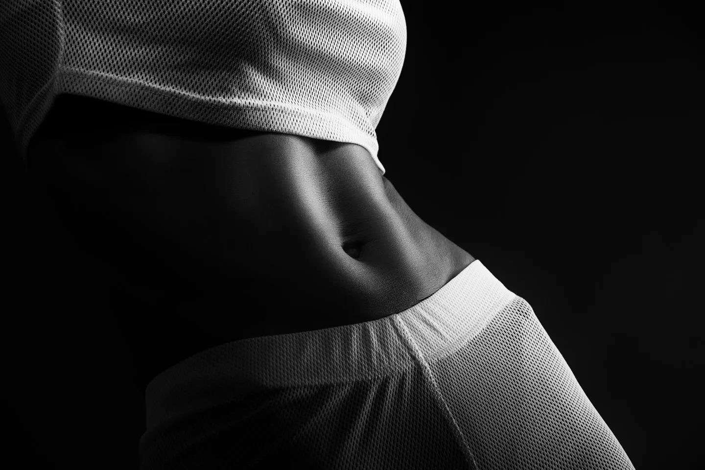 Monochrome close-up of athletic torso and mesh clothing