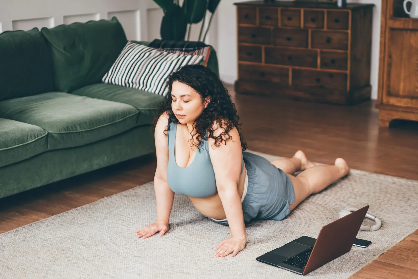 Woman doing yoga pose at home with laptop.