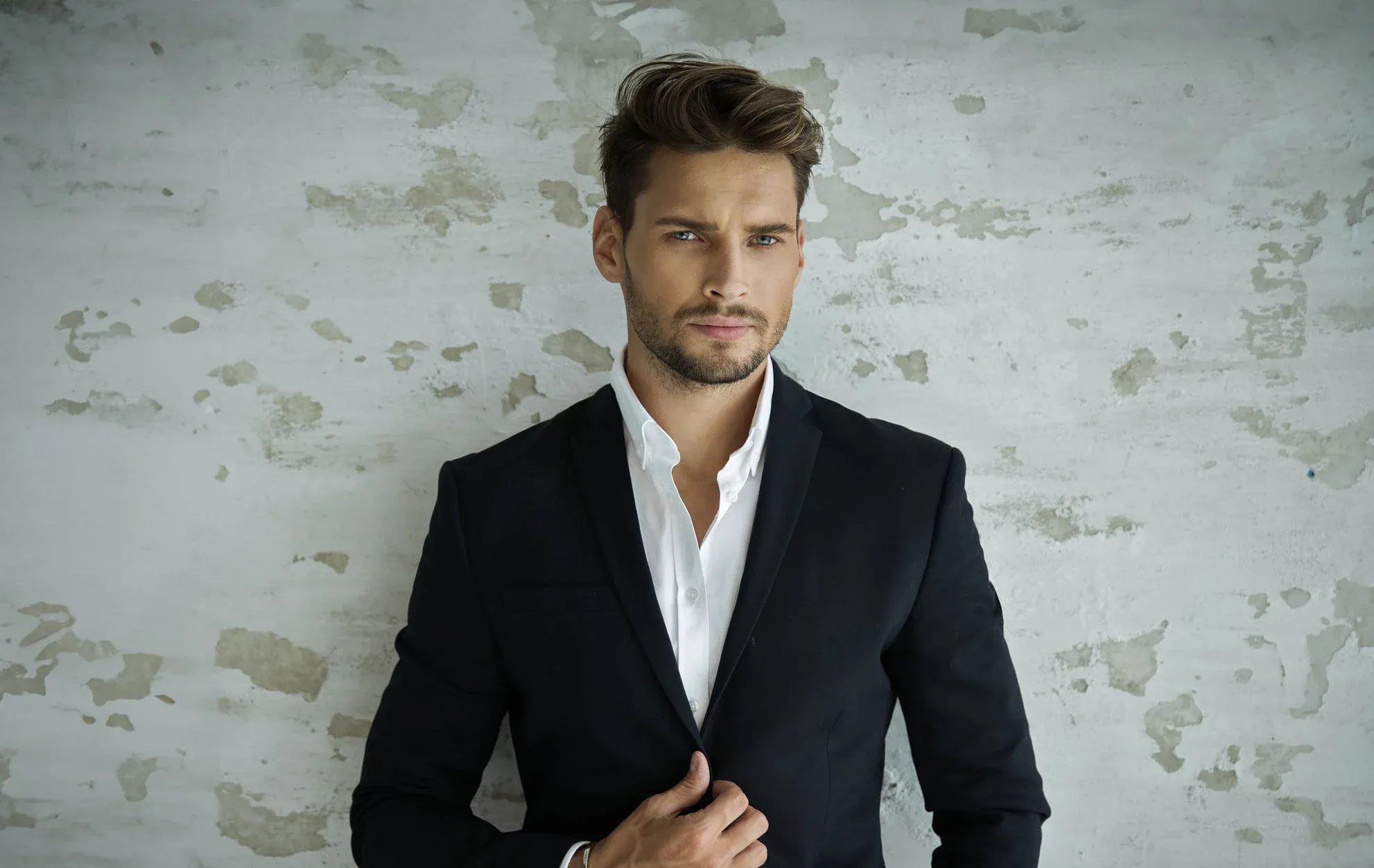 Man in black suit against textured wall