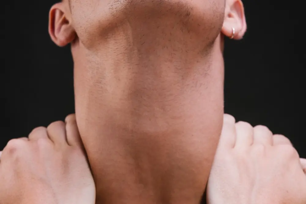 A close-up of a man's neck and jawline being tilted back and manually lifted
