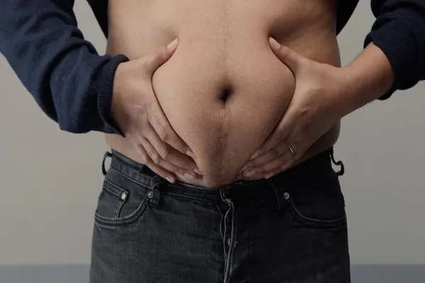 A man holding his stomach to show his obesity
