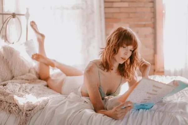 A woman on a bed reading about tummy tuck procedures